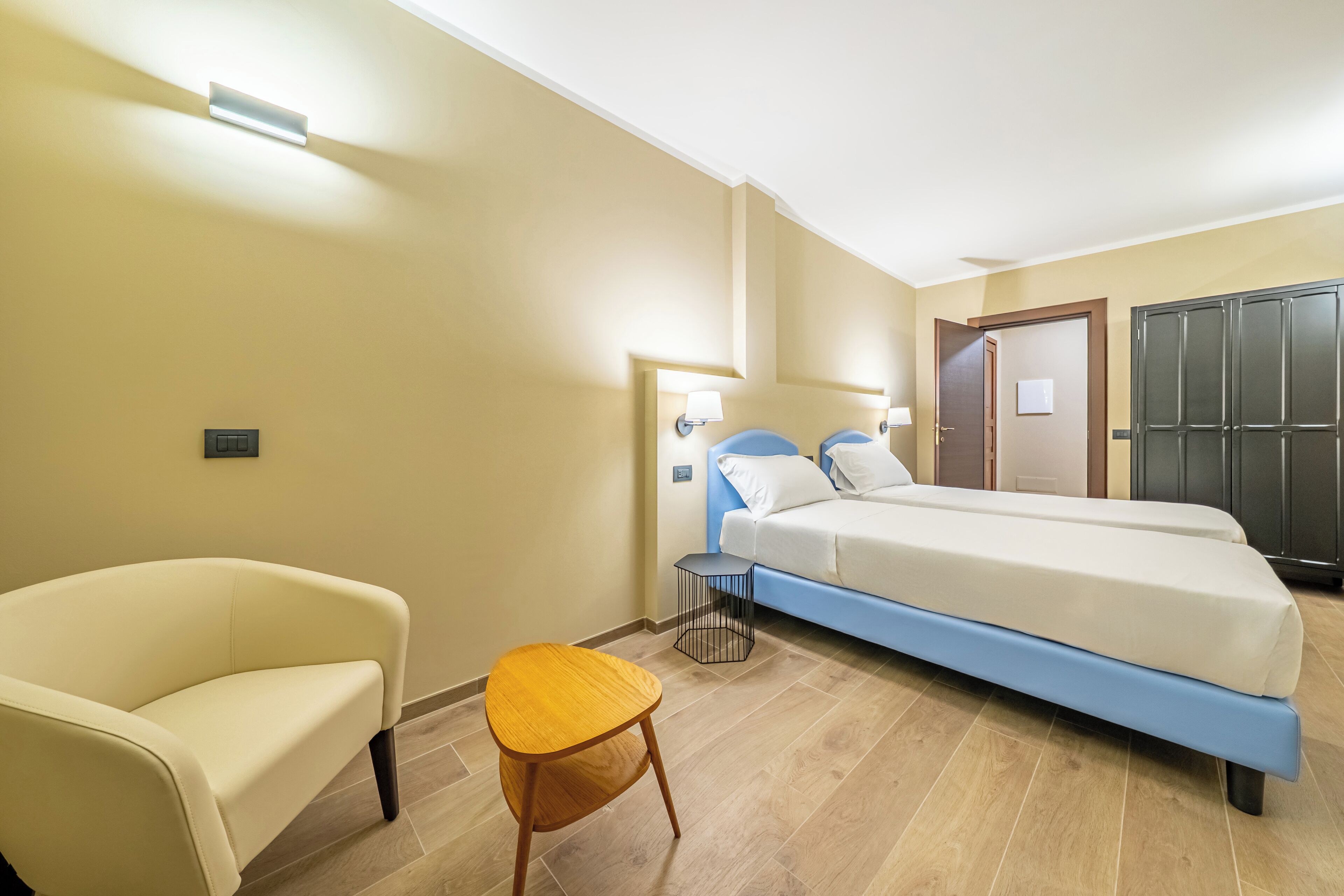 Ein Schlafzimmer mit Bett, Stuhl, einem kleinen Tisch und einem Kleiderschrank.