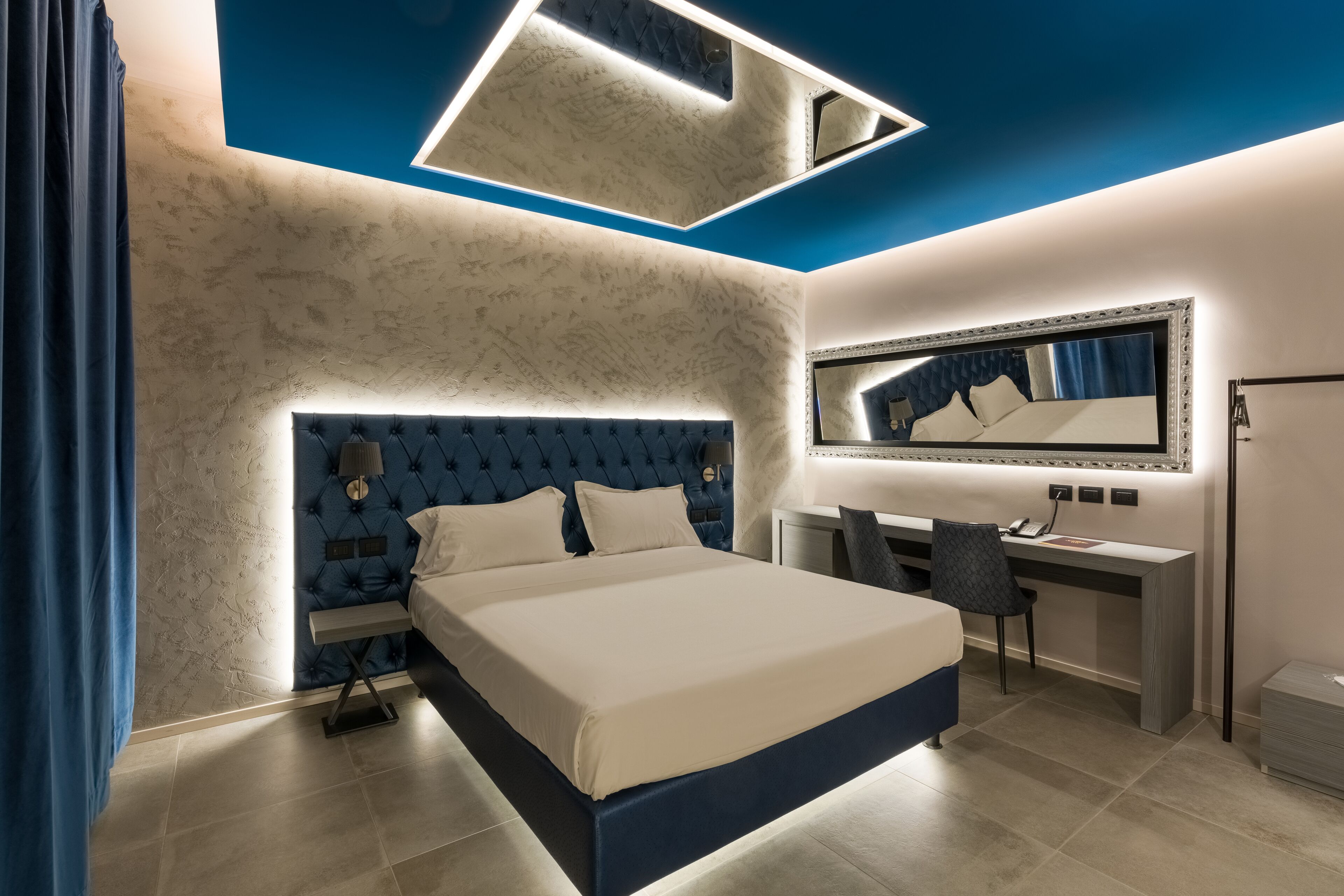 Un dormitorio moderno con una cama grande, un escritorio y un espejo.