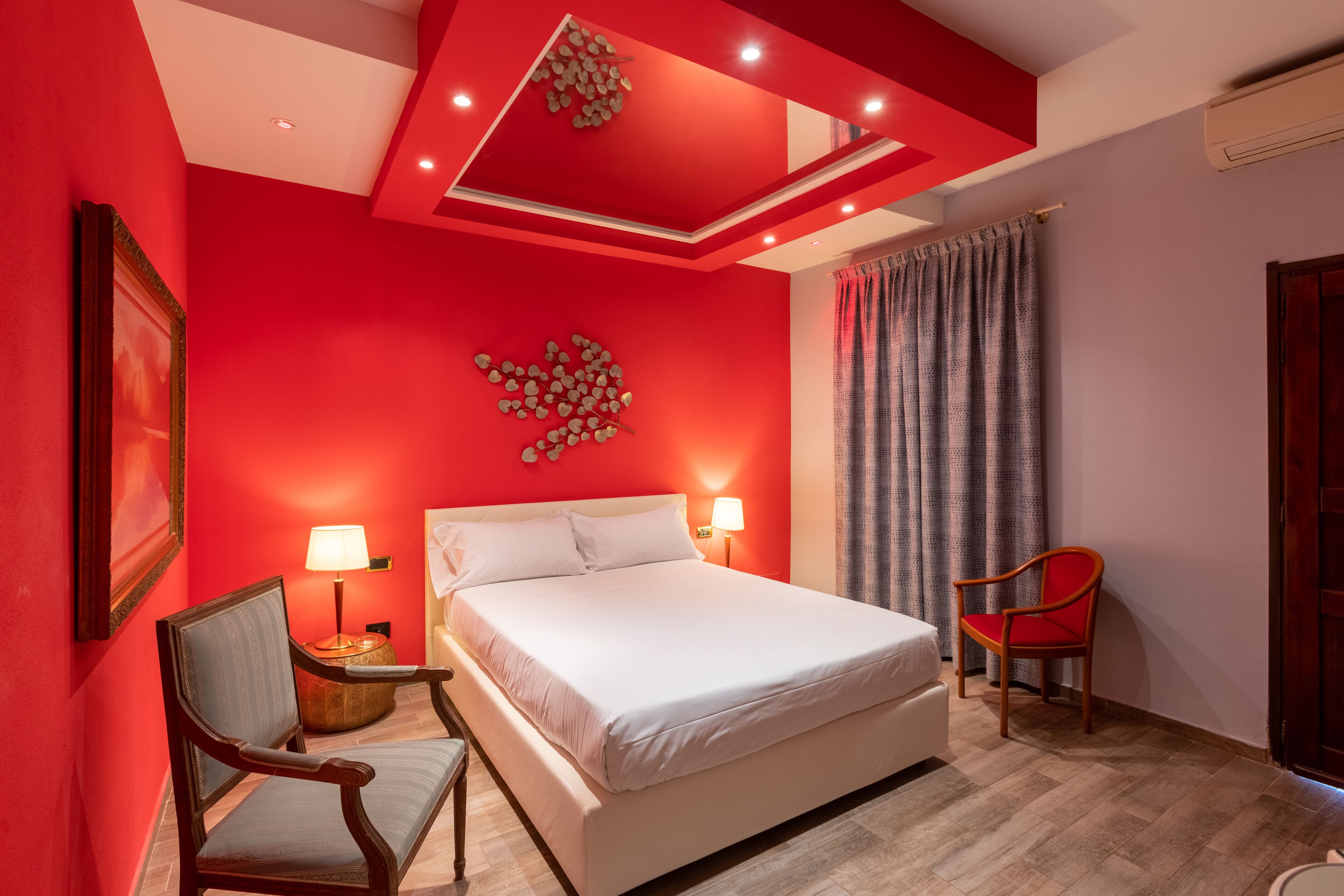 A bedroom with a large bed, two bedside lamps, a chair, and a decorative wall piece.
