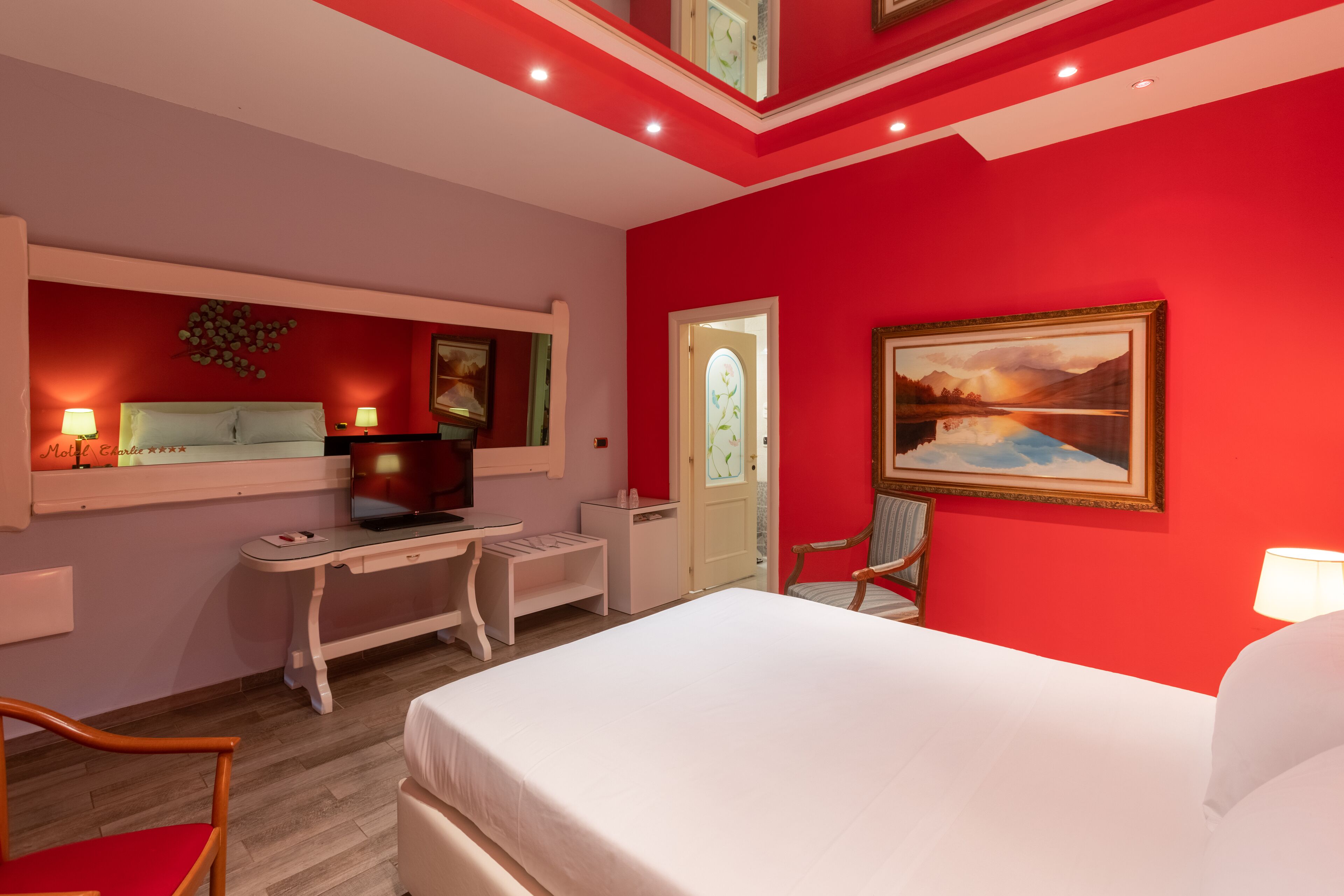 Une chambre d’hôtel avec un lit, un bureau, une chaise et un tableau au mur.