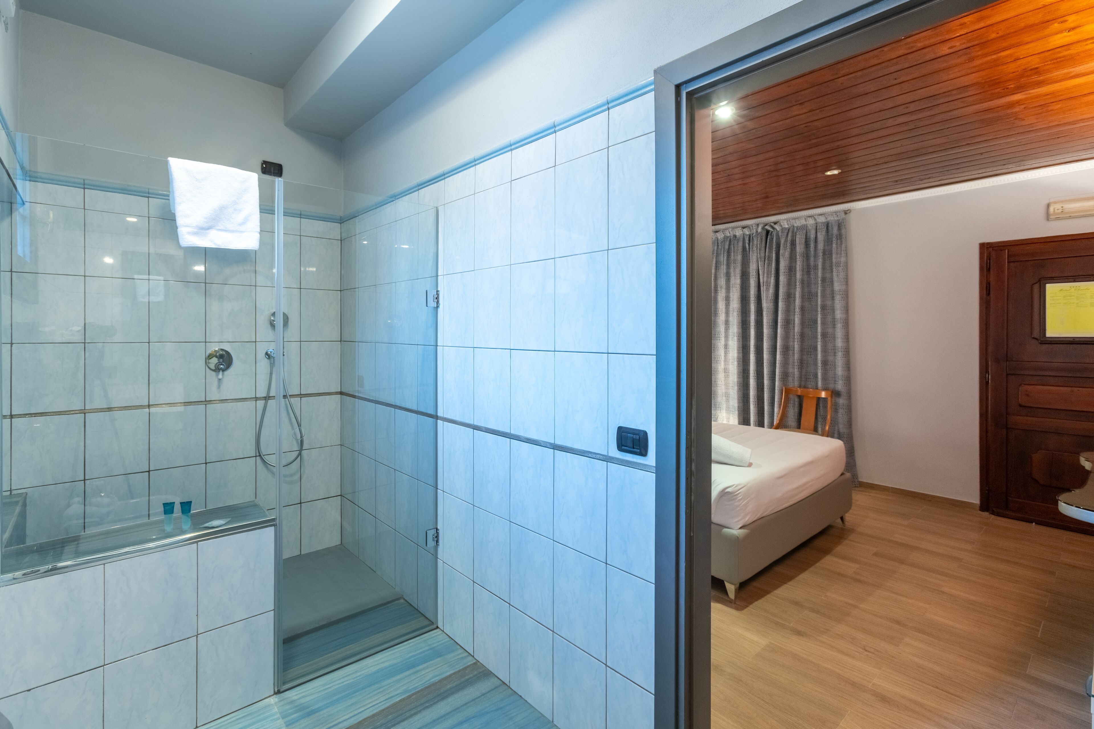 Un baño moderno con cabina de ducha de vidrio, inodoro separado y suelo de madera.