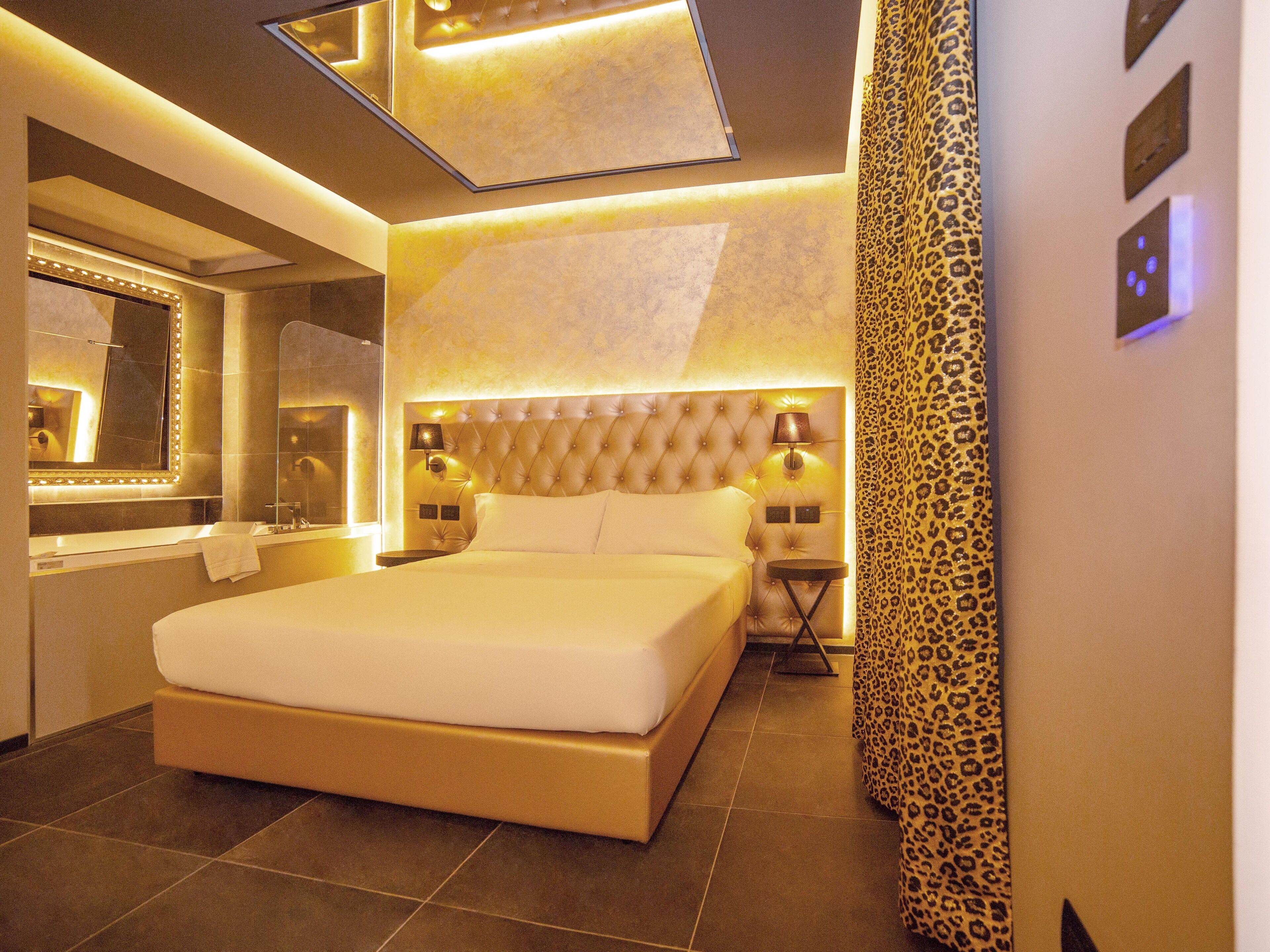 A modern hotel room with a large bed, a vanity with a mirror, and a leopard print curtain.