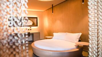 A modern bedroom with a circular bed, a round mirror, a bedside table, and a nightstand.