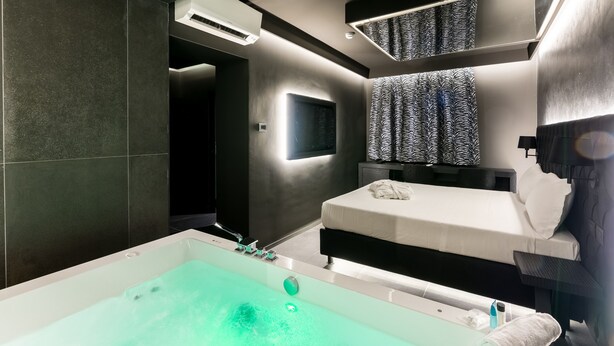 A modern bathroom with a large bathtub, a bed, and a shower area. - CHARLIE HOTEL Charme & Comfort (Settala)