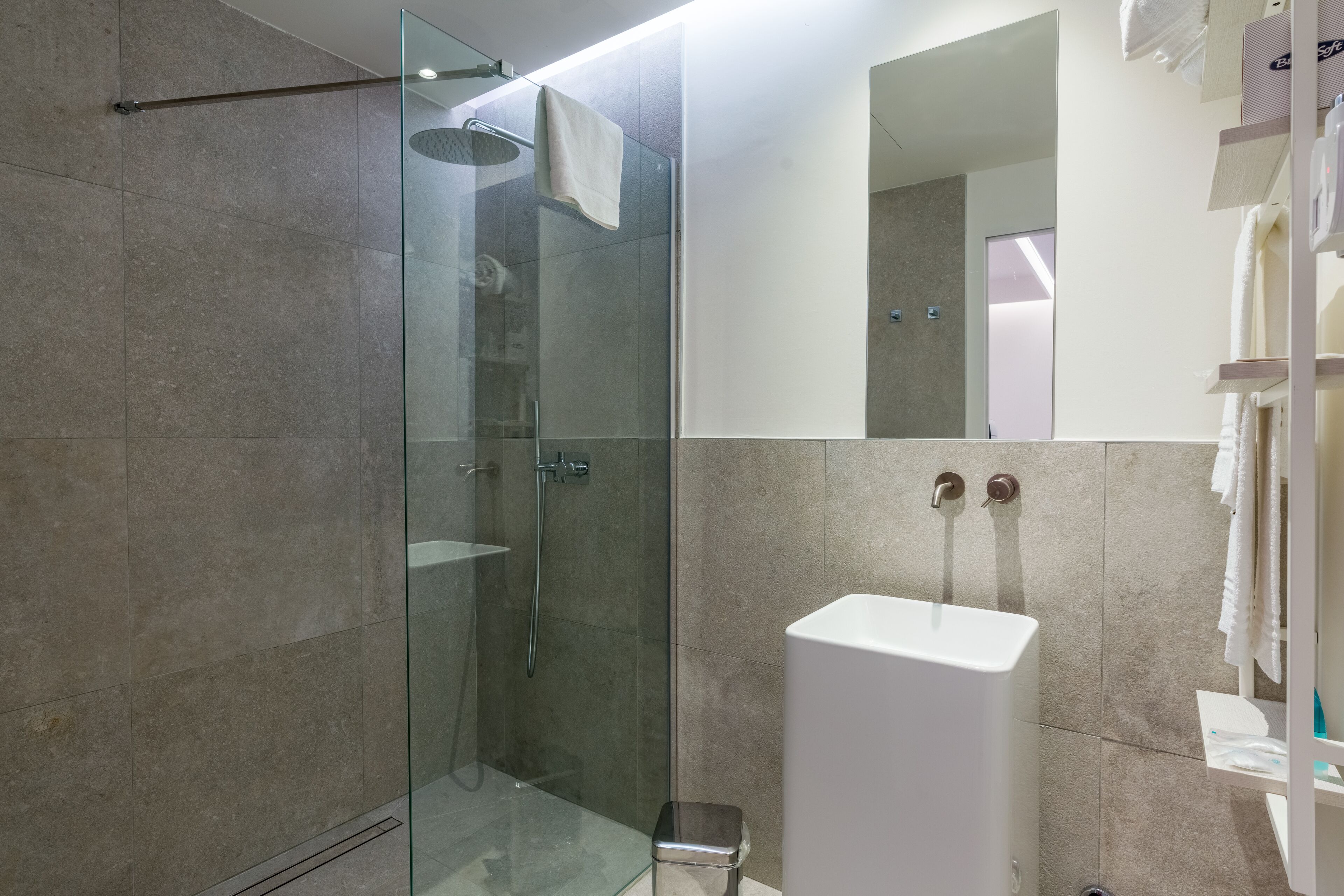 Une salle de bain moderne avec une douche à parois de verre, un lavabo blanc et un miroir au-dessus.