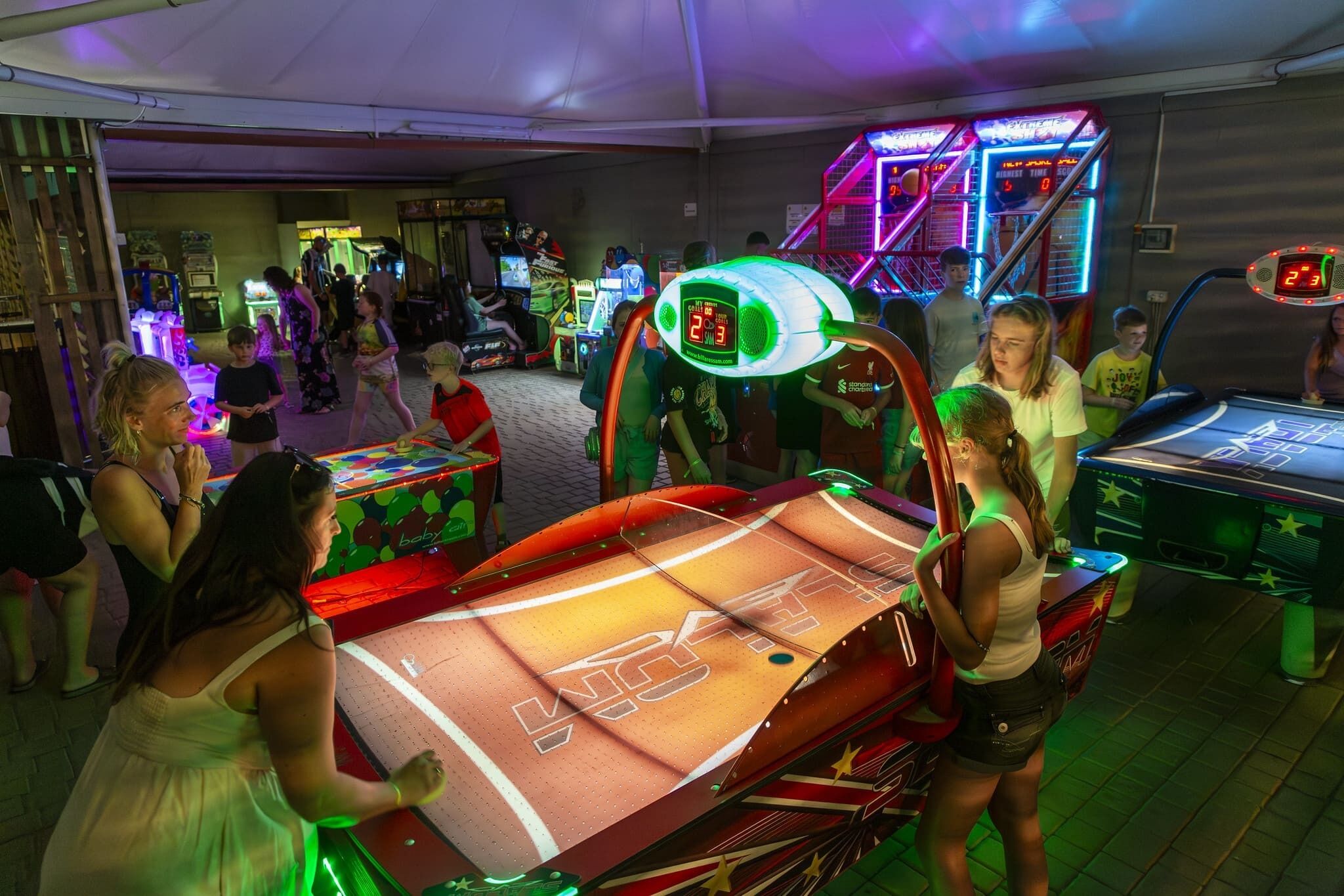 A gaming arcade with various machines, including a table tennis table and a claw machine.
