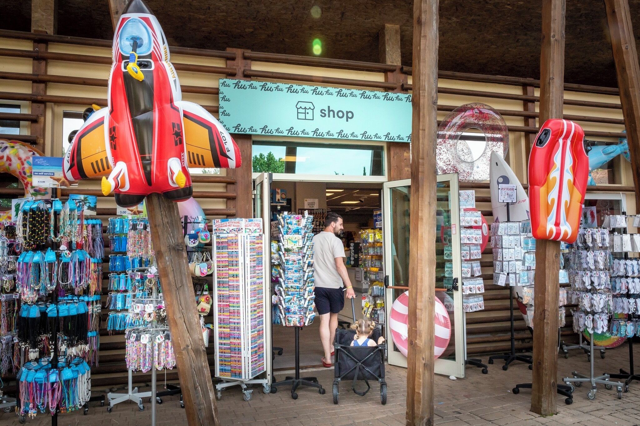 A shop with a sign reading "shop" and various items displayed outside, including bags and accessories.
