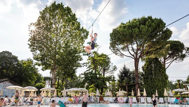 A pool area with lounge chairs and umbrellas, surrounded by trees. - Hotel La Diga - Altomincio Family Park (Valeggio sul Mincio)