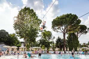 A pool area with lounge chairs and umbrellas, surrounded by trees. - Hotel La Diga - Altomincio Family Park (Valeggio sul Mincio)