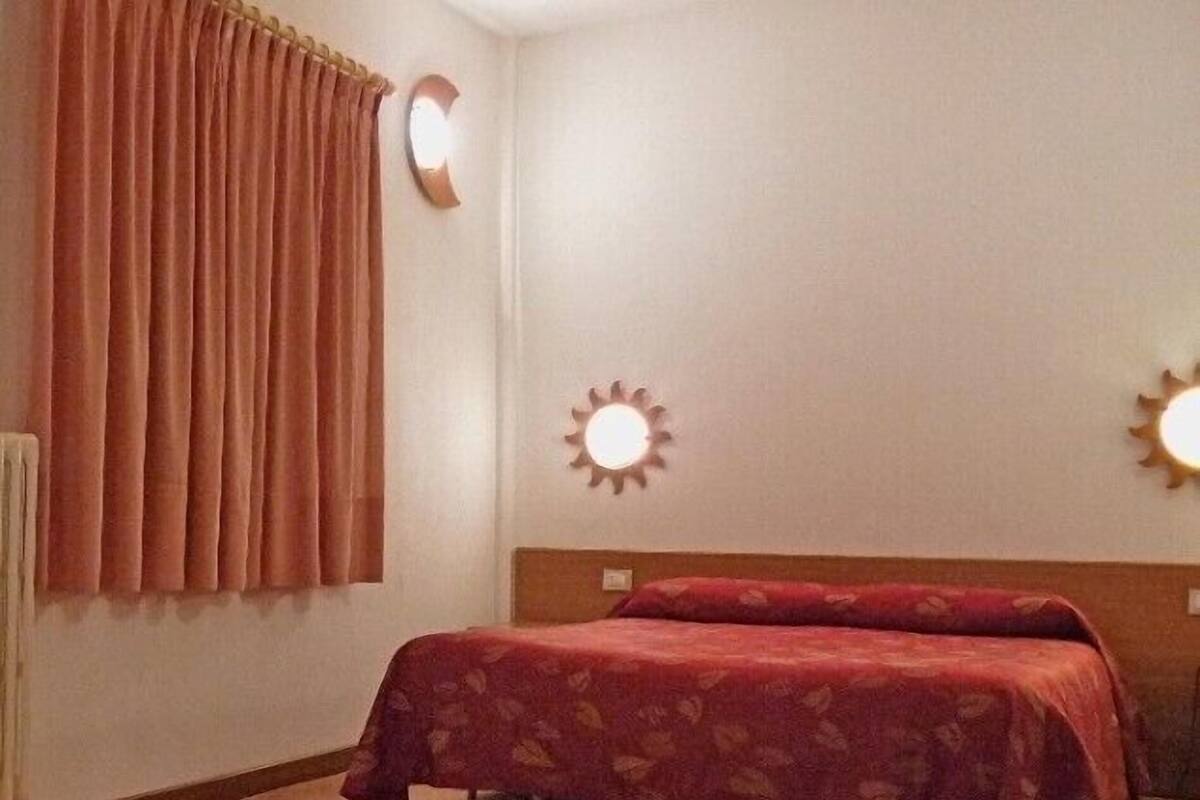 A bedroom with a bed, curtains, and wall-mounted lights.