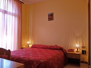 Une chambre d’hôtel avec un lit, un bureau et deux lampes de chevet.