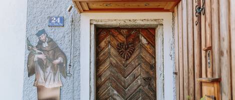 Una puerta de madera con un diseño en forma de chevron y un adorno de guirnalda con forma de corazón. Un cartel sobre la puerta dice "24 Dr. F. Morton-Weg".