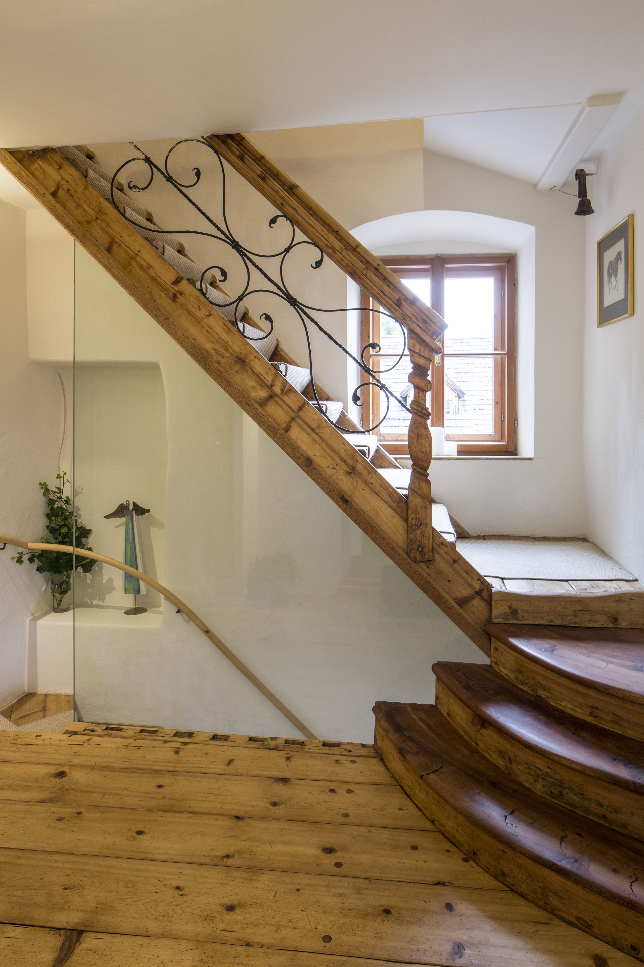 A wooden staircase with a wrought iron balustrade leading to a landing.