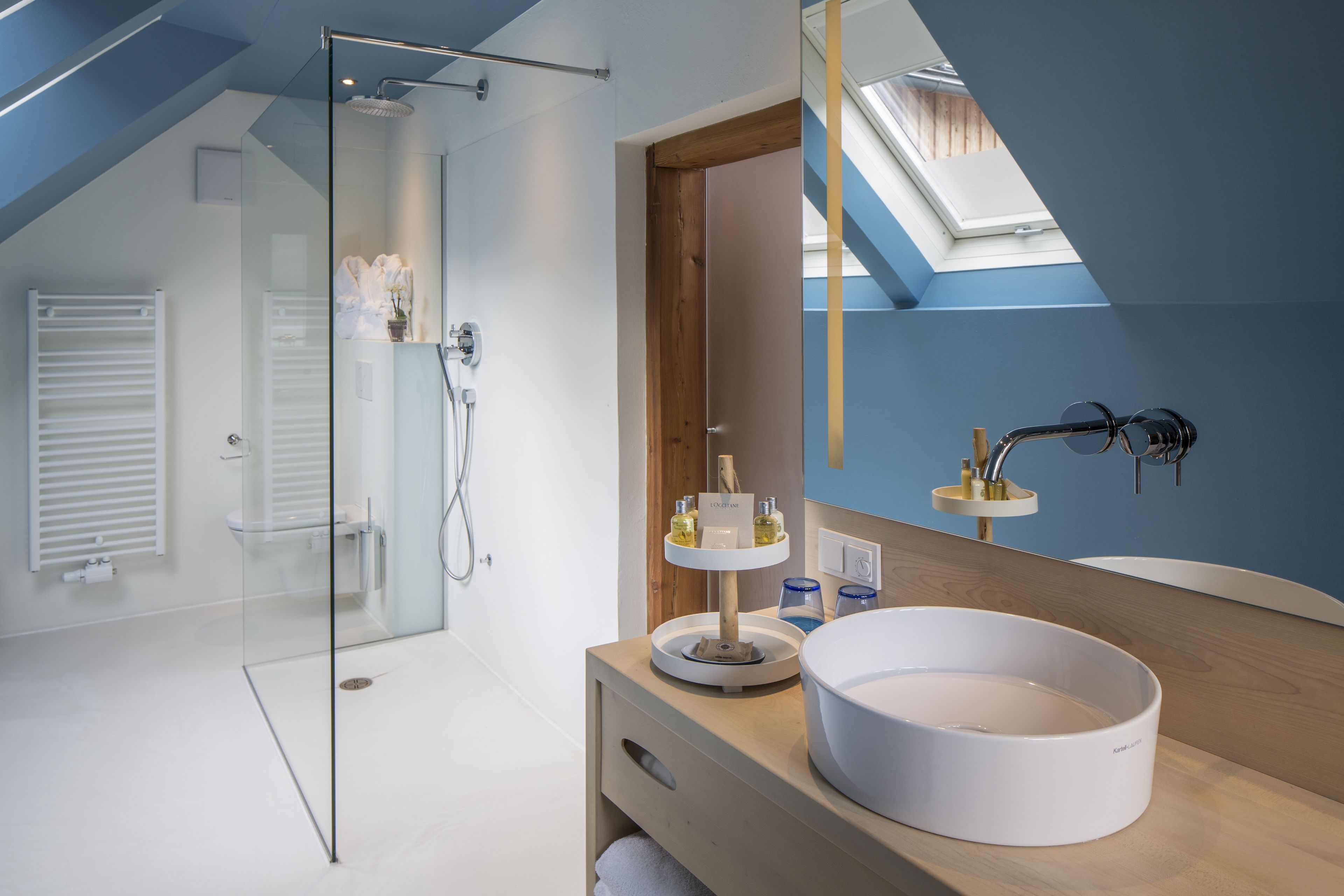 Ein modernes Badezimmer mit Duschkabine aus Glas, einem Holzbadezimmer-Waschtisch und einem Oberlicht.