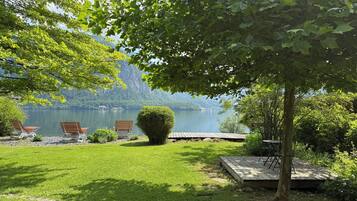 A lakeside garden with a bench, a small stage, and a view of a lake and mountains.