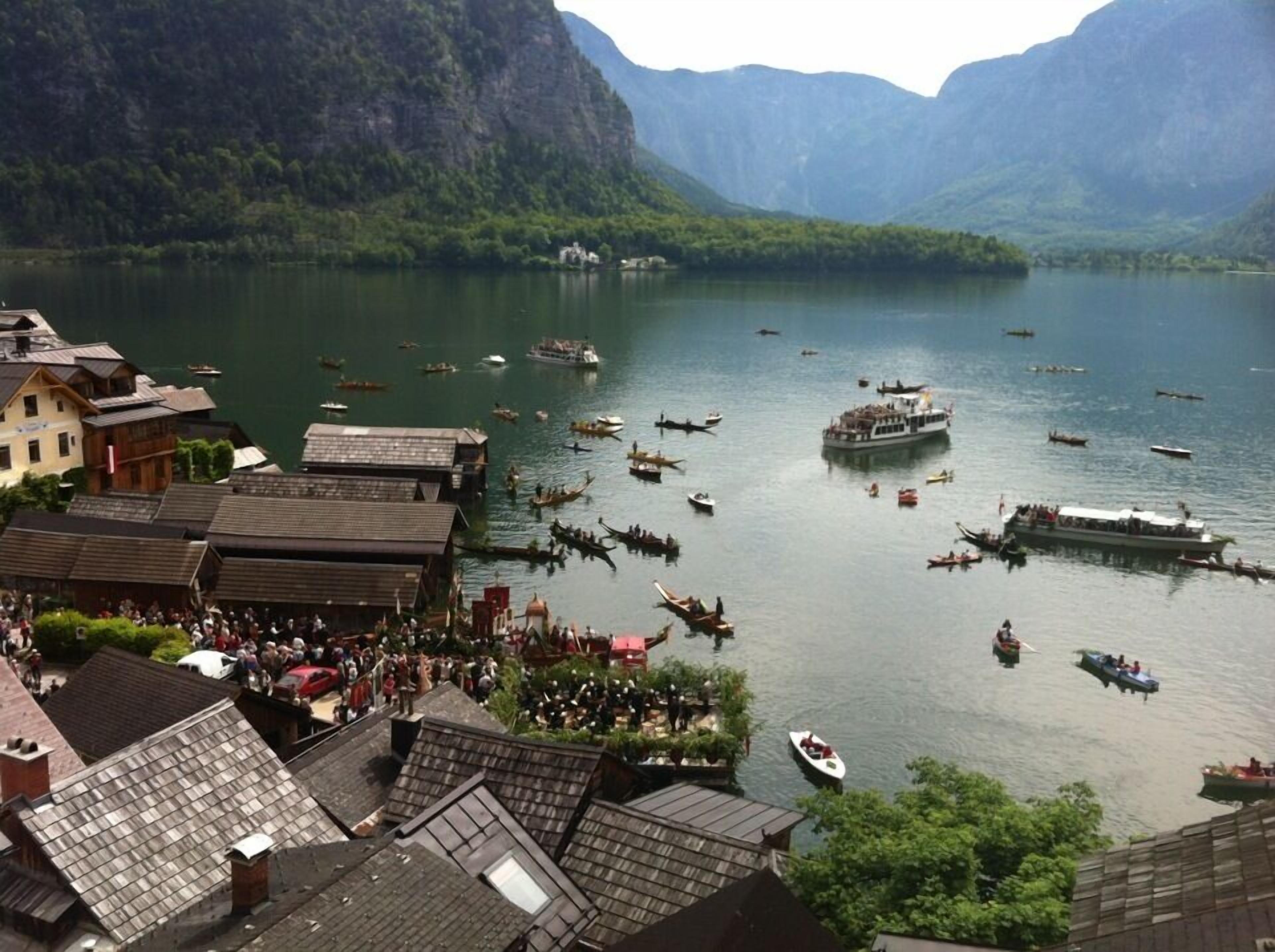 A lakeside village with traditional wooden houses, boats on the water, and mountains in the background.