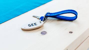 A keychain with the word "SEE" on it, lying on a wooden surface.