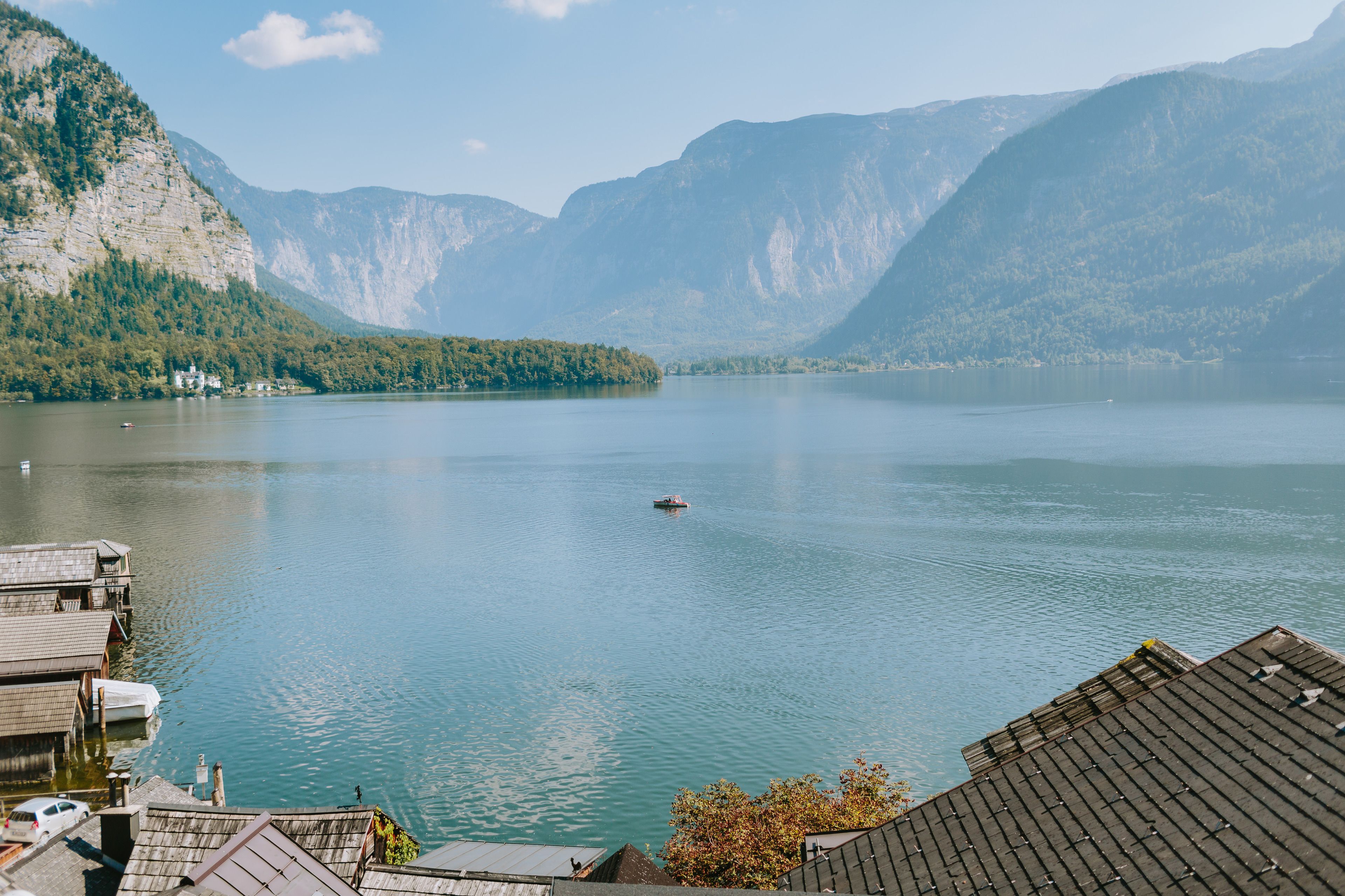 Un lac où l’on peut naviguer, entouré de montagnes et bordé d’un petit village avec quelques bâtiments.