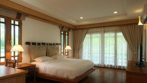 Ein geräumiges Schlafzimmer mit einem großen Bett, Holzboden und einem Schreibtisch mit Lampe.