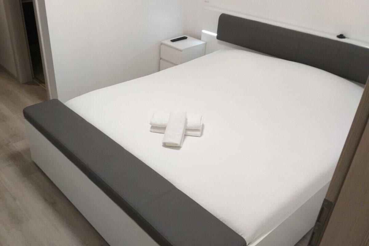 A modern hotel room with a large bed, a bedside table, and a small nightstand.