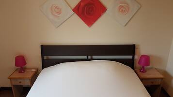 A bedroom with a bed, two bedside tables, and three wall-mounted artworks.