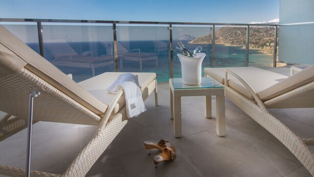 A balcony with wicker chairs, a glass table, and a vase with a bottle. - ESTIMAR Calpe Suitopia (Calpe)