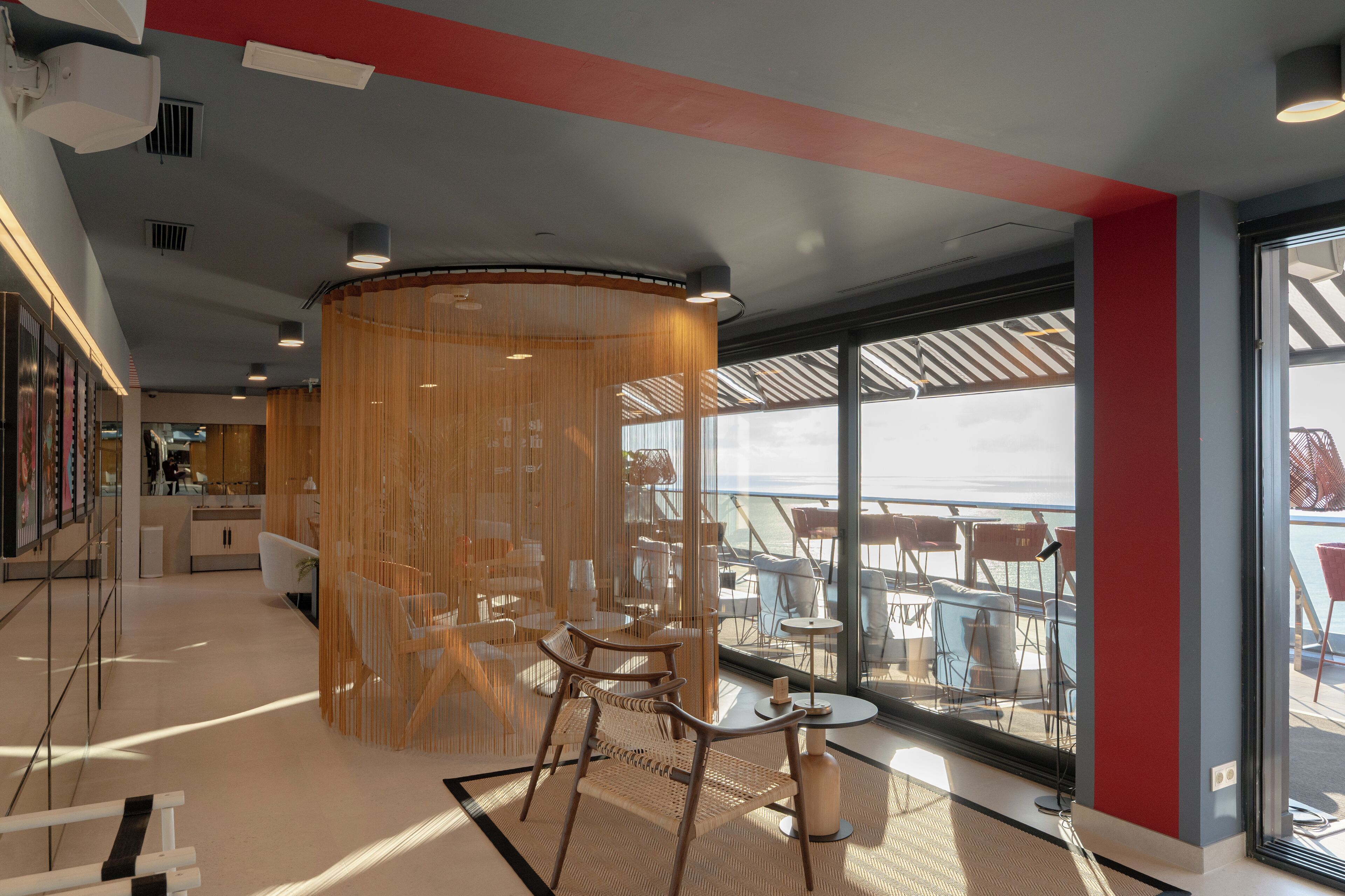 A modern interior with a seating area, large windows, and a view of the sea.