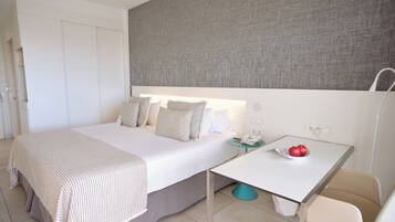 Una habitación de hotel con cama, mesita de noche y un pequeño escritorio con un frutero.