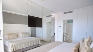 A modern bedroom with a large bed, a smaller bed, a TV, and a walk-in closet. - ESTIMAR Calpe Suitopia (Calpe)