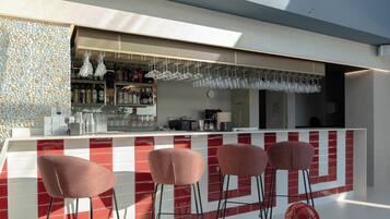 A modern bar area with a red and white tiled backsplash, a bar counter, and four bar stools.