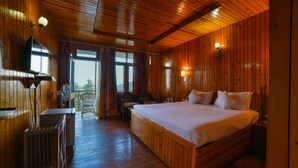 A wooden-paneled bedroom with a large bed, a desk, and a chair. - Mint Tarika Resort (Kandaghat)