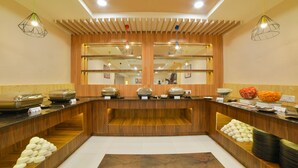 A buffet area with multiple serving stations, a central open space, and a variety of food items displayed. - Mint Tarika Resort (Kandaghat)