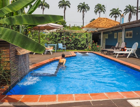 Una piscina al aire libre, sombrillas, sillones reclinables de piscina