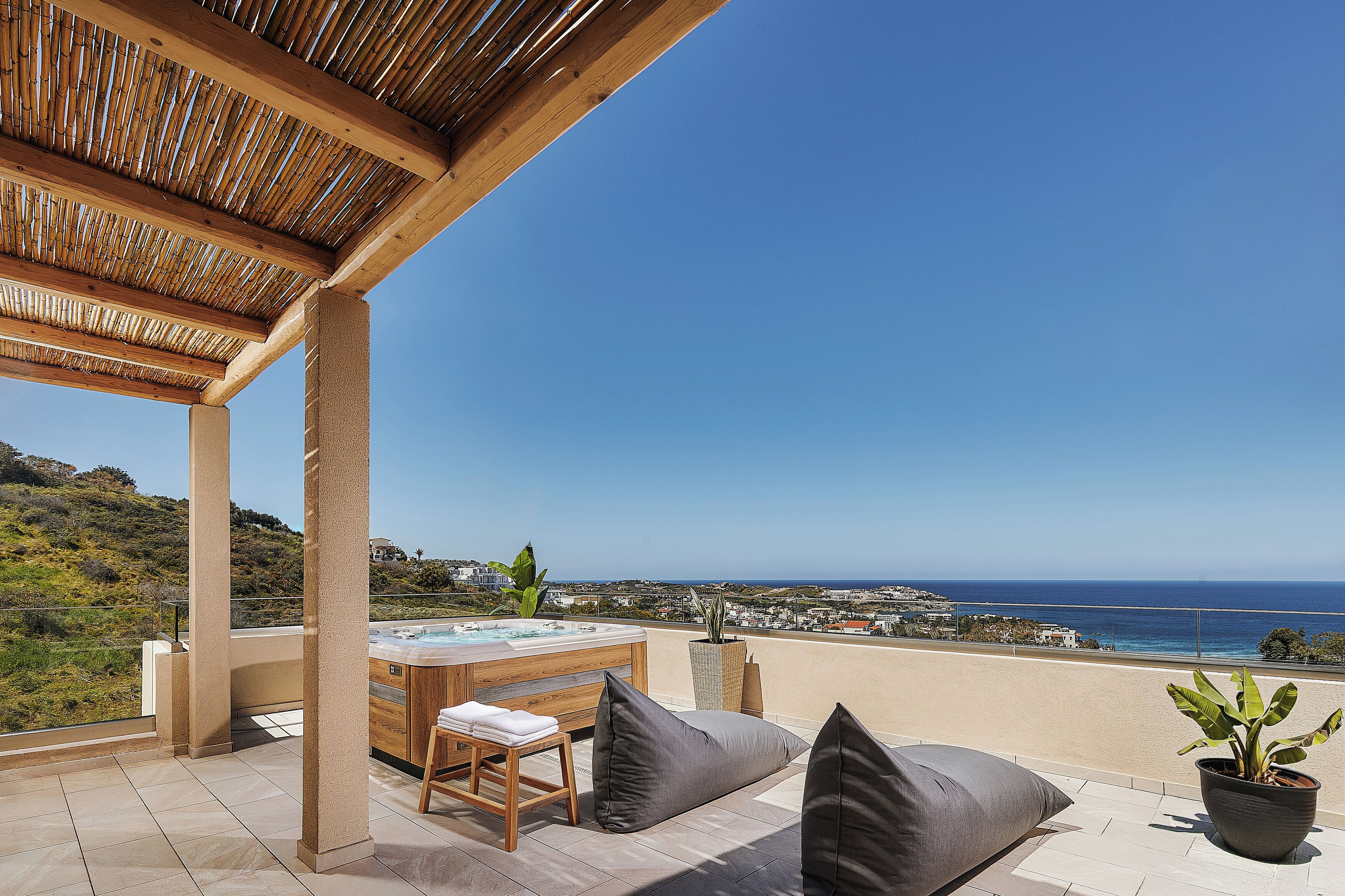 A terrace with a hot tub, seating, and a view of the sea.