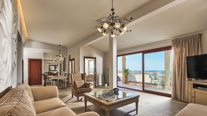 A spacious living room with a large window, a dining area, and a TV. - OZEA - Elevated Living (Malevizi)