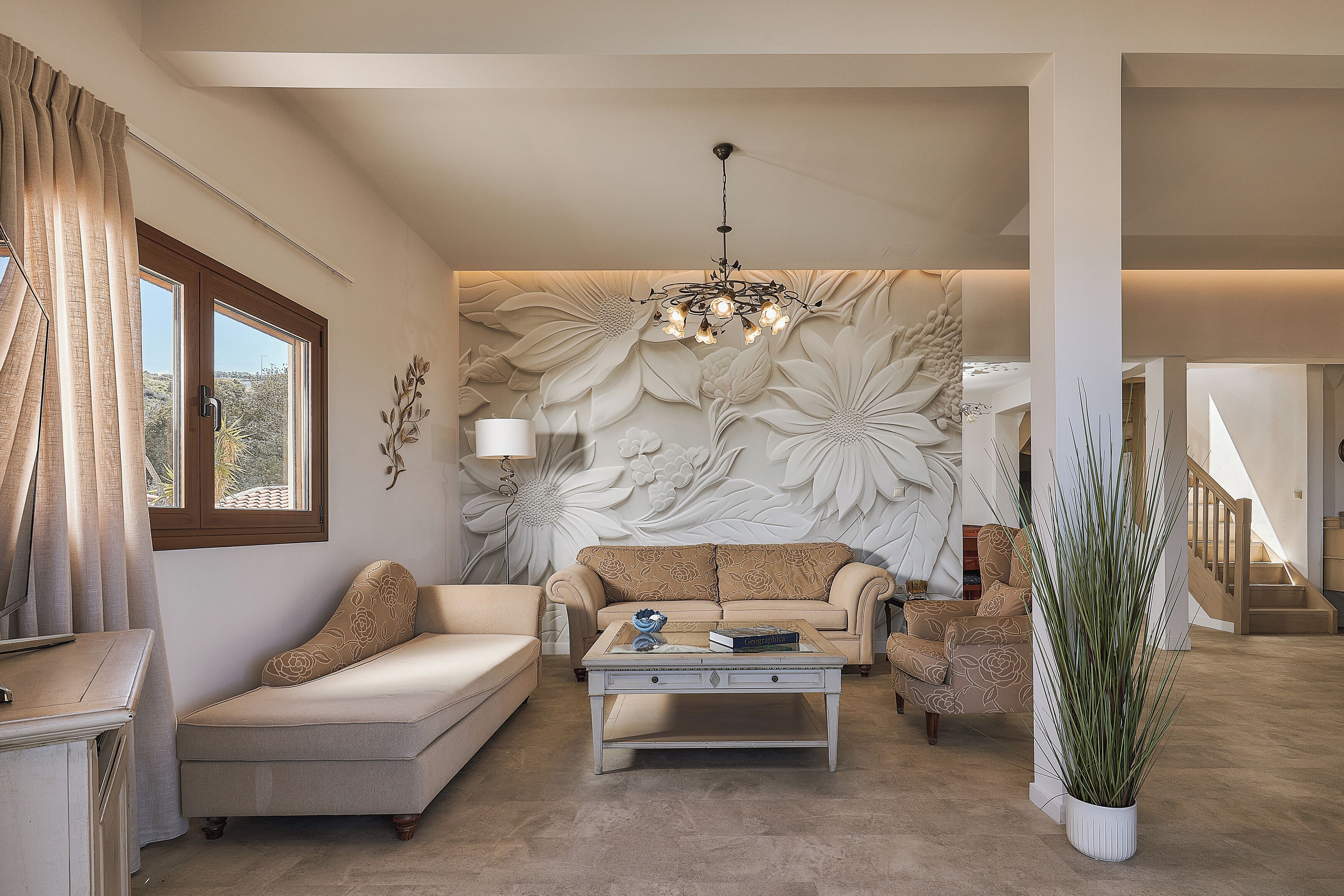 A living room with a sofa, armchair, coffee table, and a large potted plant.