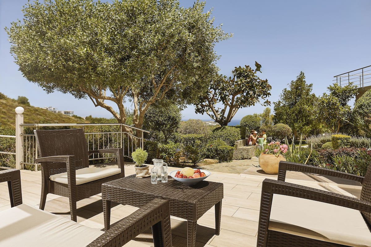 An outdoor patio with wicker furniture, a bowl of fruit, and a potted plant.