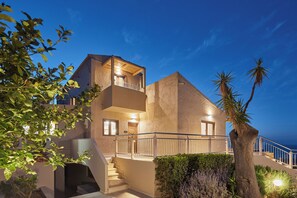 Un immeuble de deux étages doté d’un balcon, d’un escalier et offrant une vue sur la mer.