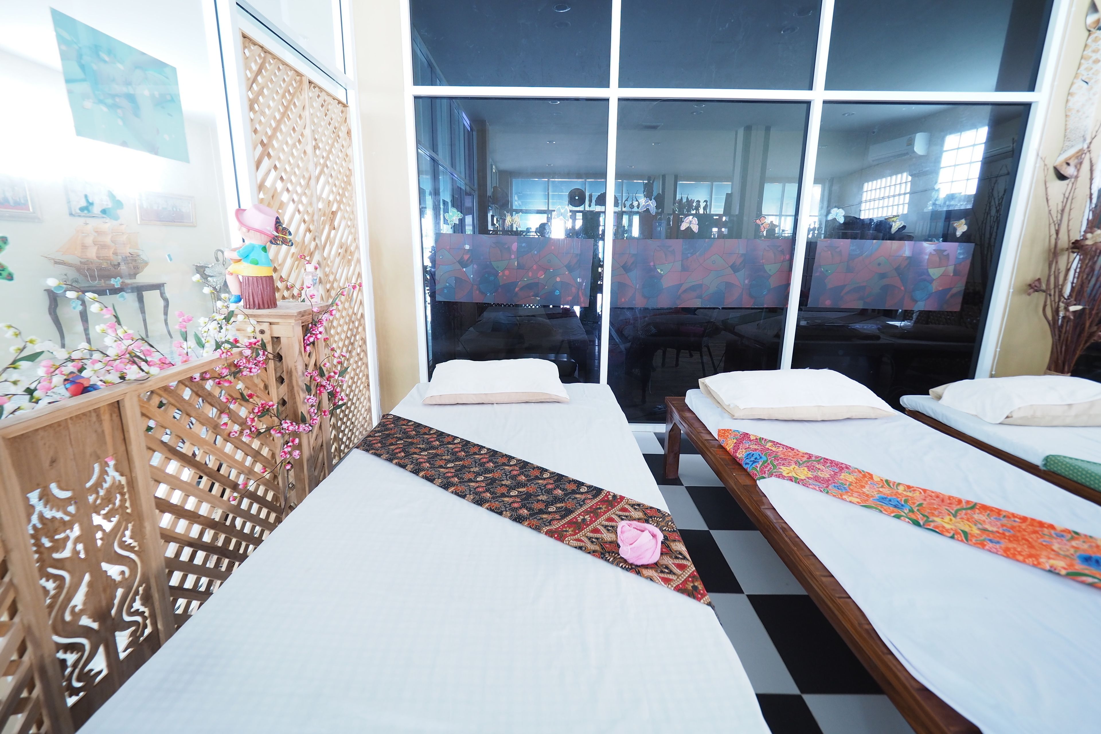 Habitación de hotel con dos camas, un separador de madera y vistas amplias a través de grandes ventanales.