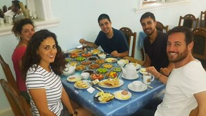 Un grupo de personas sentadas alrededor de una mesa con varios platos, sugiriendo un ambiente de comida compartida.