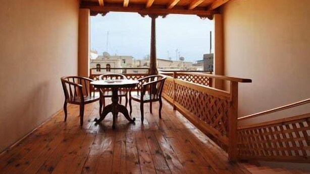 Un balcón de madera con una mesa y sillas, con vistas a un paisaje urbano.