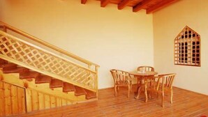Una escalera de madera con barandilla de celosía que lleva a un comedor con mesa y sillas.