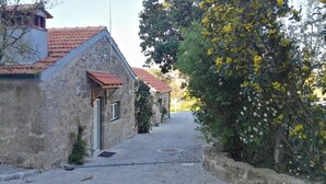 Une ruelle étroite pavée, bordée de bâtiments en pierre coiffés de toits de tuiles rouges.