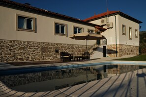 A house with a stone facade, a swimming pool, and outdoor furniture. - Quinta de Vodra (Seia)