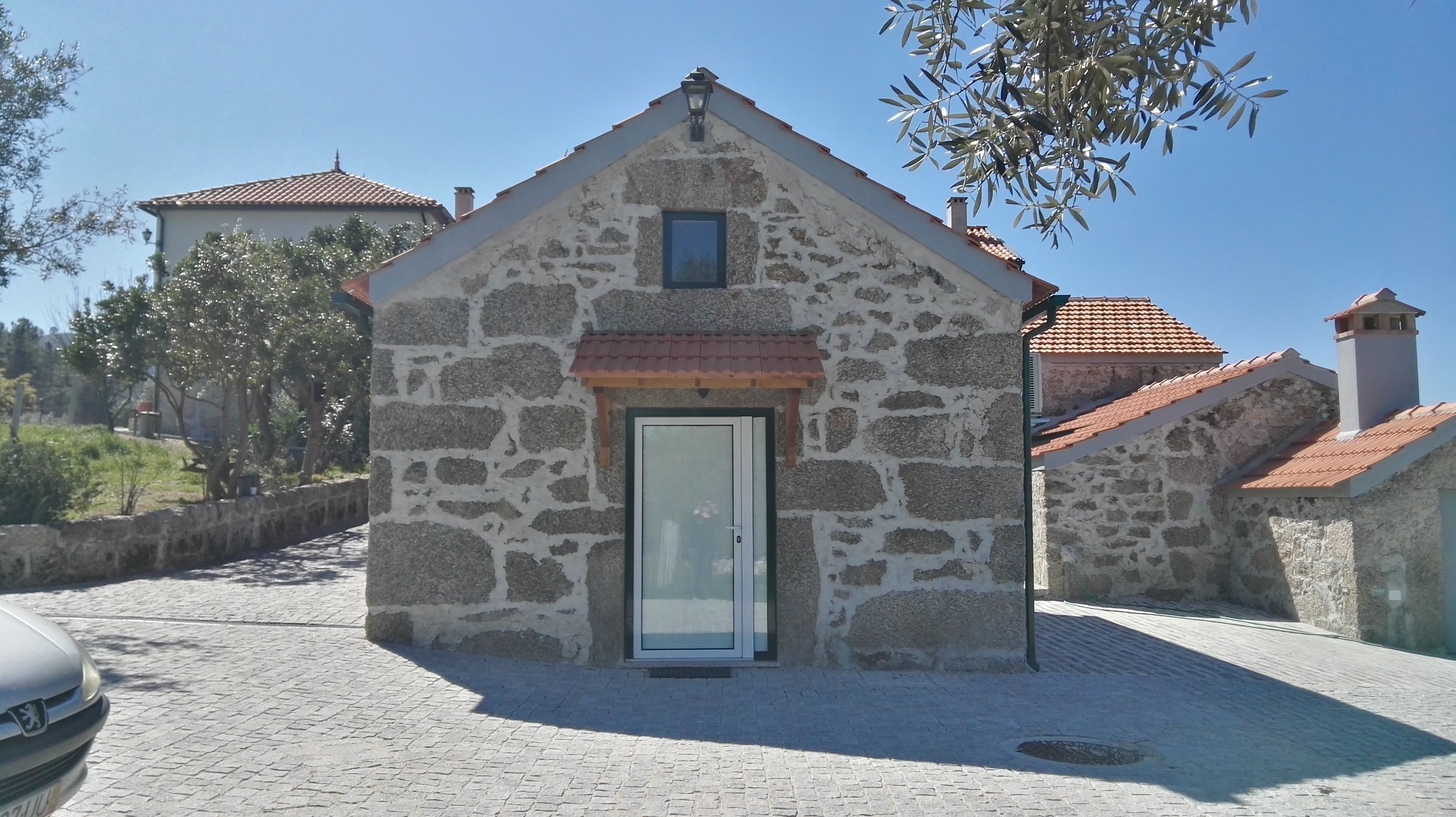 A stone building with a tiled roof, a small window, and a door.