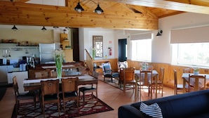 Un vaste espace de vie doté d’un plafond en bois et d’un coin repas avec une table et des chaises en bois.
