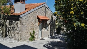 Un bâtiment en pierre avec un toit recouvert de tuiles rouges, une petite porte et une fenêtre.