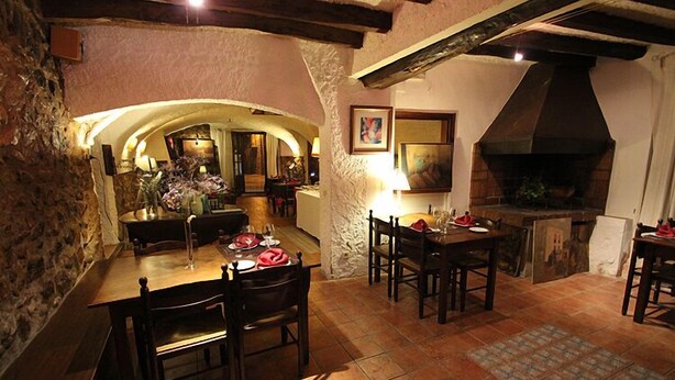 A rustic dining area with stone walls, wooden furniture, and a large fireplace. - La Fornal dels Ferrers (Terrades)