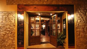 A rustic hotel entrance with stone walls, wooden doors, and a welcoming interior. - La Fornal dels Ferrers (Terrades)