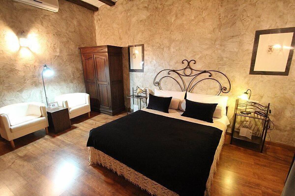 A bedroom with a large bed, a wardrobe, a desk, and a chair.